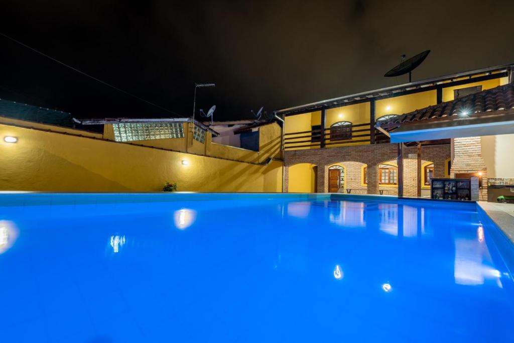 a large swimming pool in front of a building at night at Casa Temporada em Caraguá in Caraguatatuba