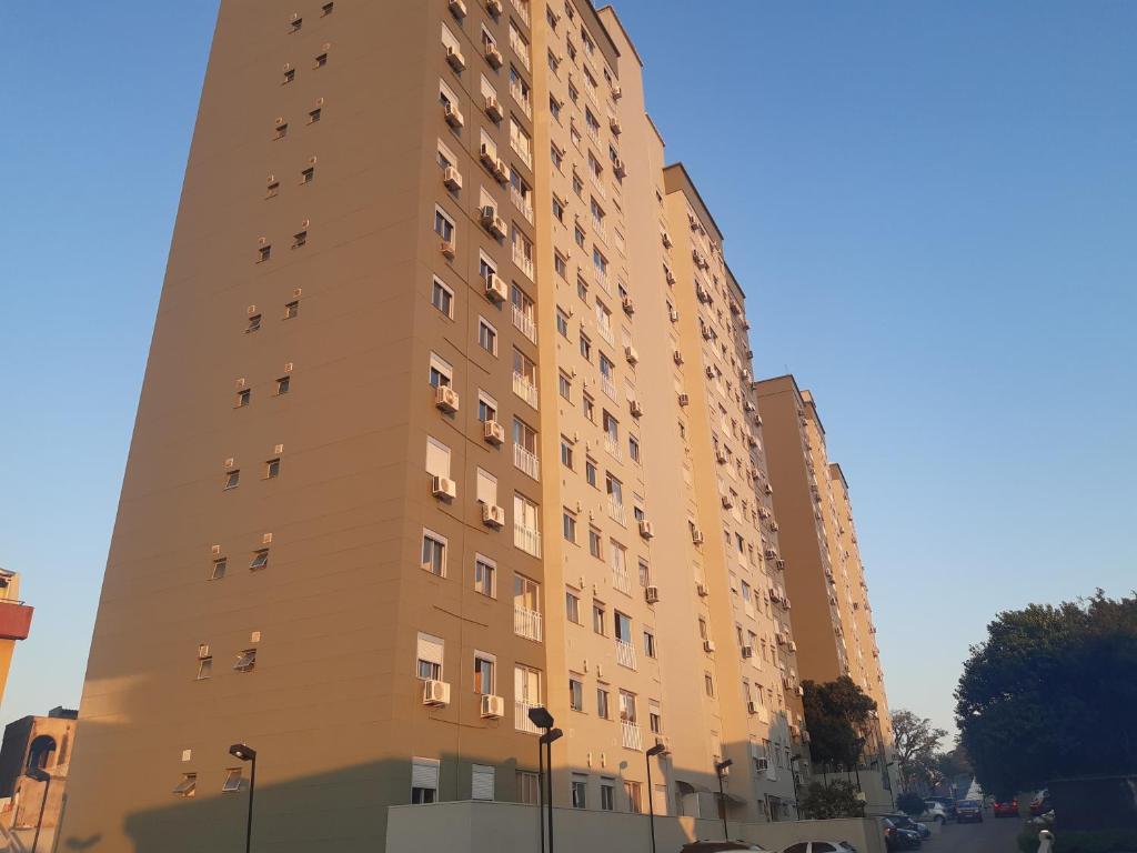 a tall tan building with windows on a street at Apartamento Dom Vital in Porto Alegre