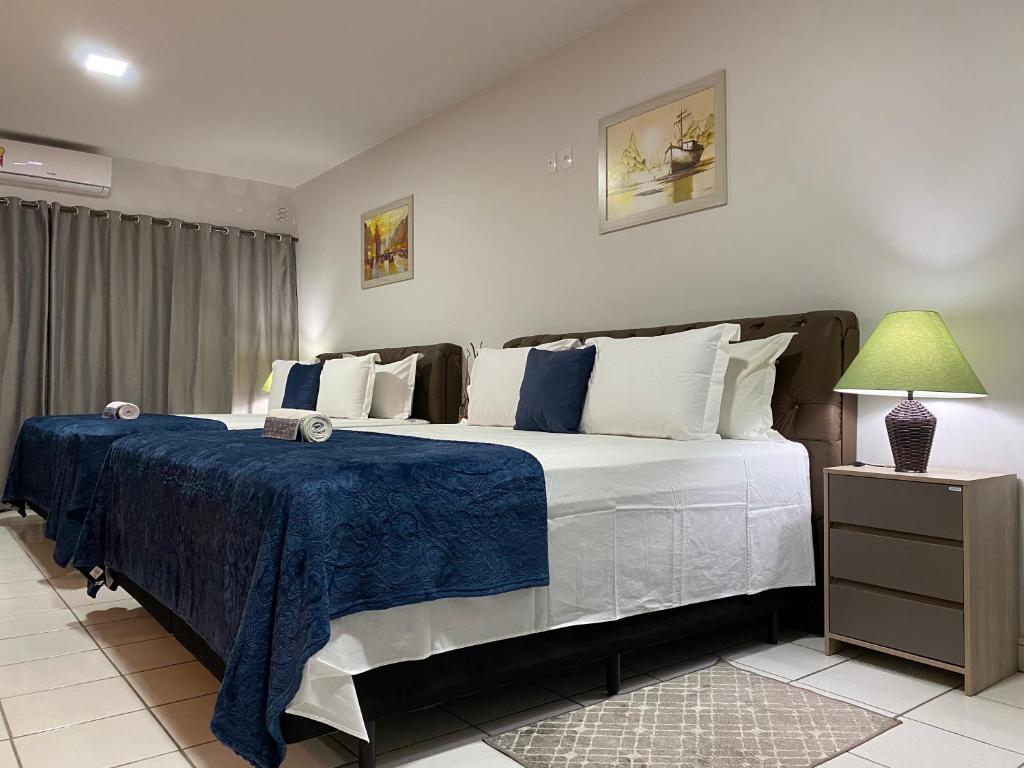 a bedroom with a large bed with a blue blanket at B & A Suites Inn Hotel - Quarto Luxo Safira in Anápolis