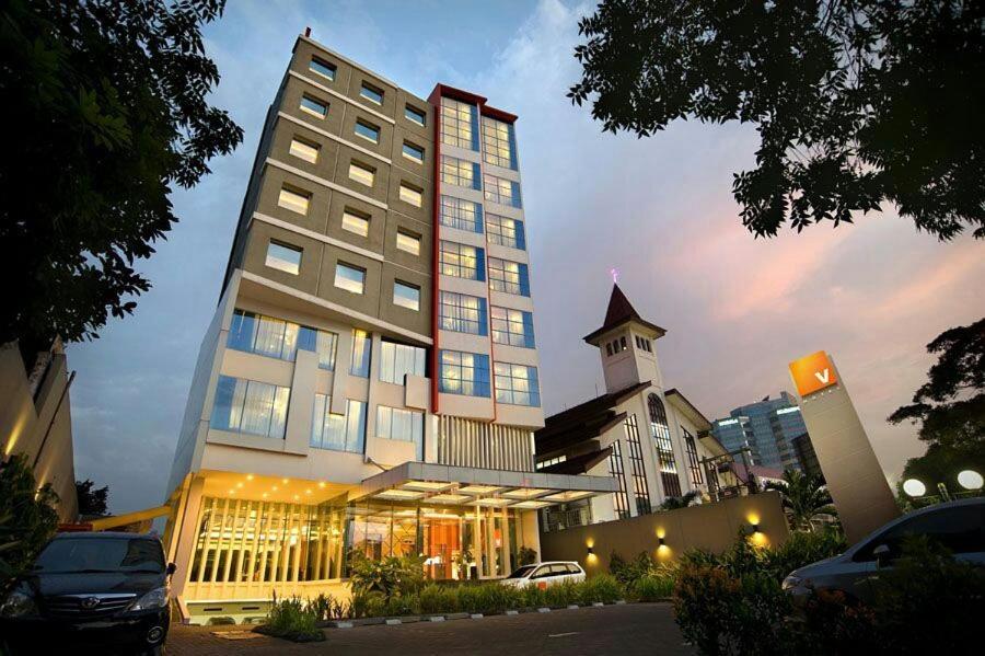 ein hohes Gebäude mit einem davor geparkt in der Unterkunft V Hotel Tebet in Jakarta