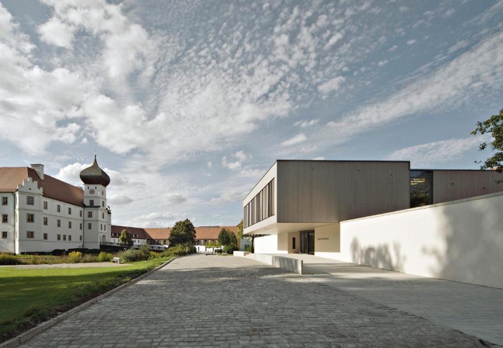 a large white building with a church in the background at Schloss Hohenkammer in Hohenkammer