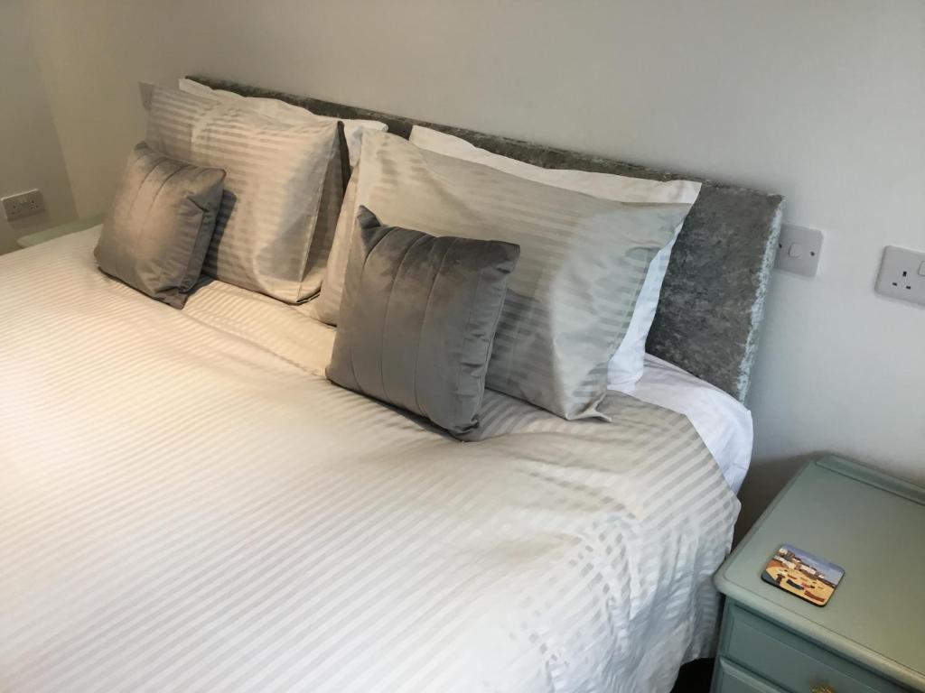 a bed with white sheets and pillows on it at Westlea Guest House in Alnmouth