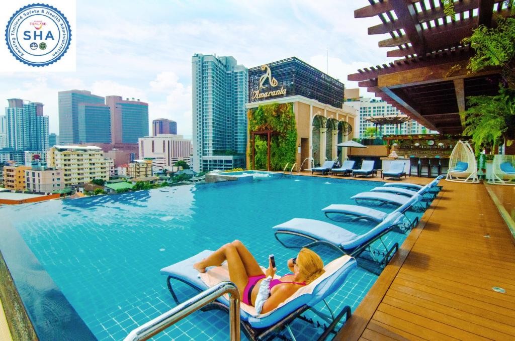 a woman laying on a lounge chair next to a swimming pool at Amaranta Hotel - SHA Plus in Bangkok