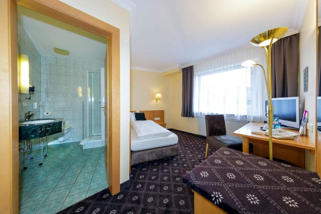 Habitación de hotel con cama y baño en Hotel Zum Adler, en Nidderau