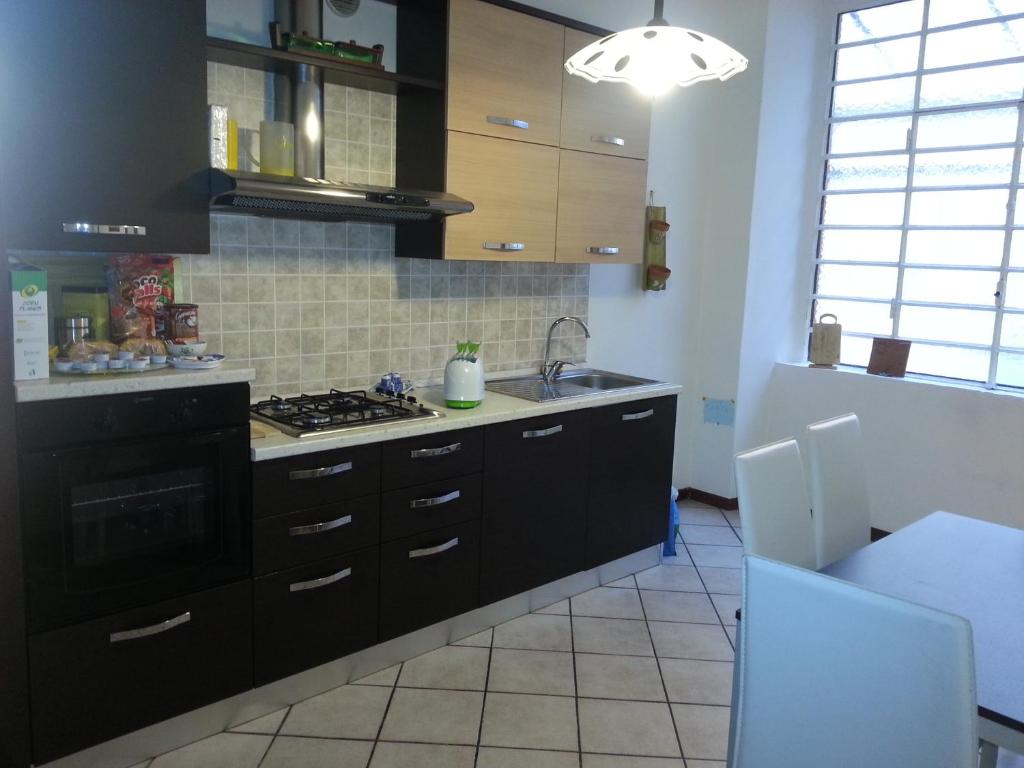 a kitchen with black cabinets and a stove top oven at B&B Smeraldo Airport in Bergamo