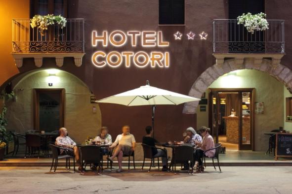 a group of people sitting at tables in front of a hotel at Hotel Cotori in El Pont de Suert