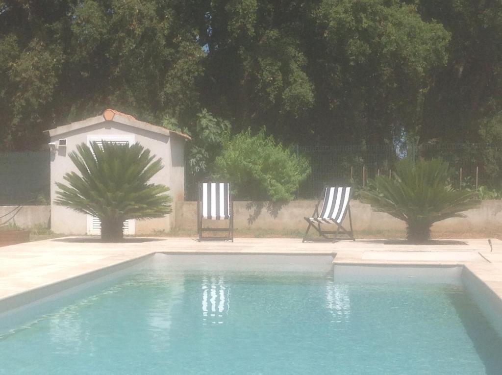 Duas cadeiras estão sentadas ao lado de uma piscina em Cavone 2 em Castellare-di-Casinca
