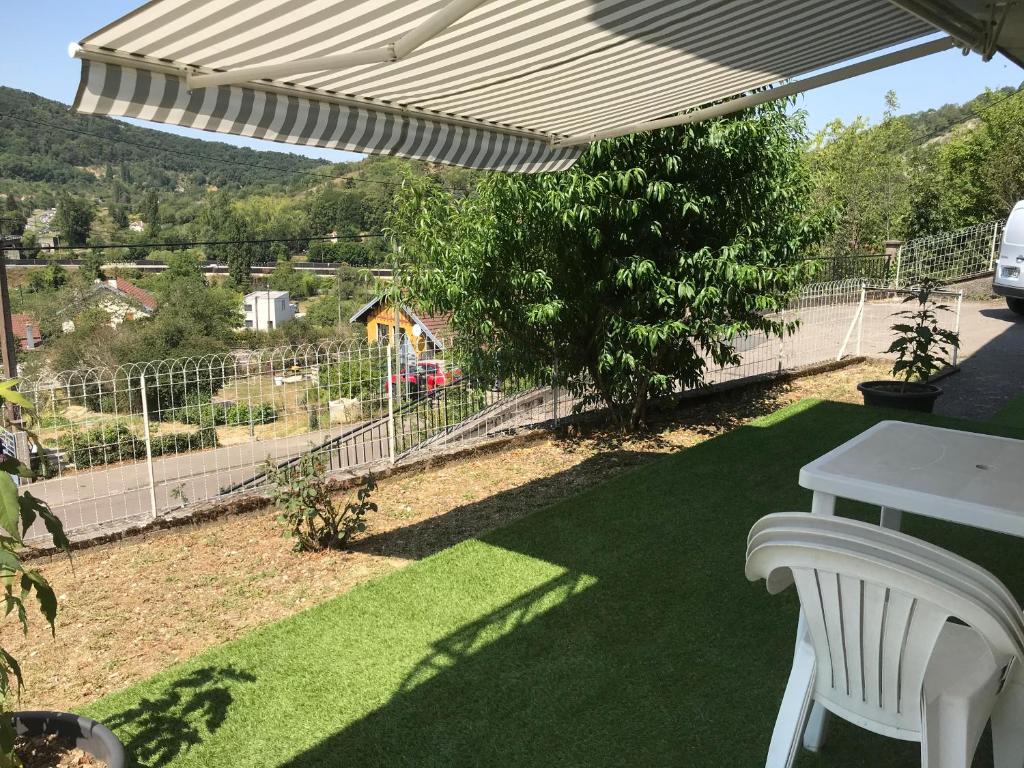 eine Terrasse mit einem weißen Stuhl und einem Sonnenschirm in der Unterkunft Chez DouKine in Beure