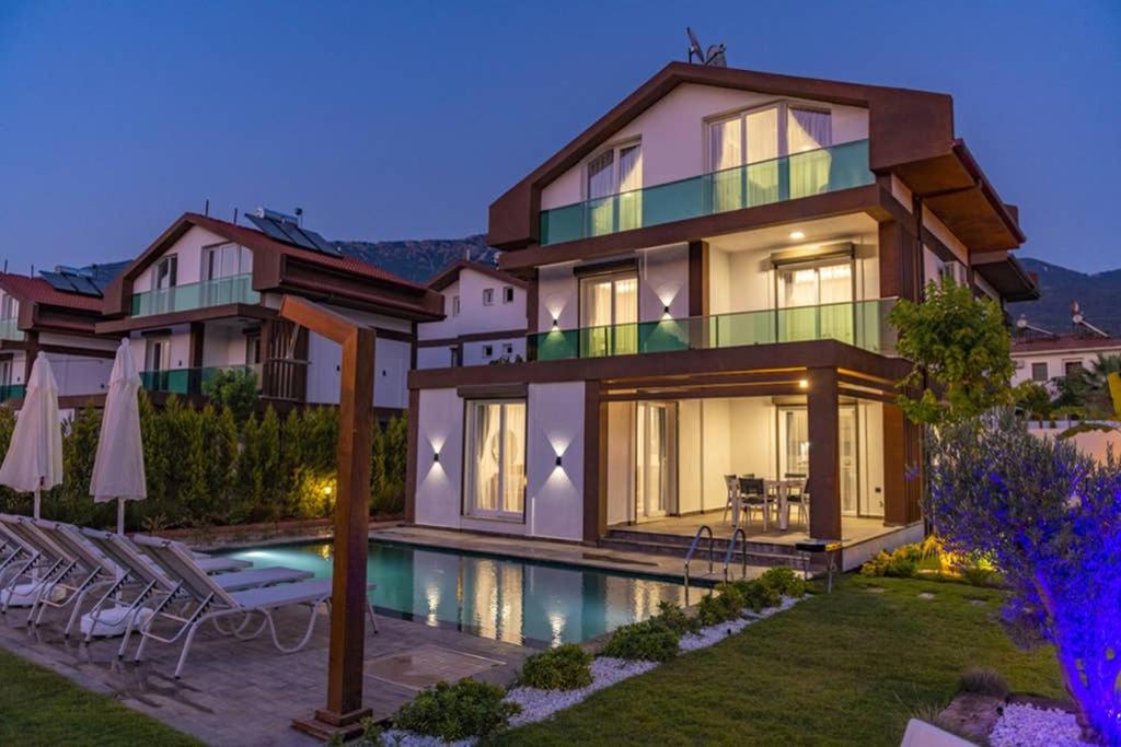 une grande maison avec une piscine en face de celle-ci dans l'établissement Bella- 4 Bedroom Holiday Villa in Oludeniz, à Fethiye