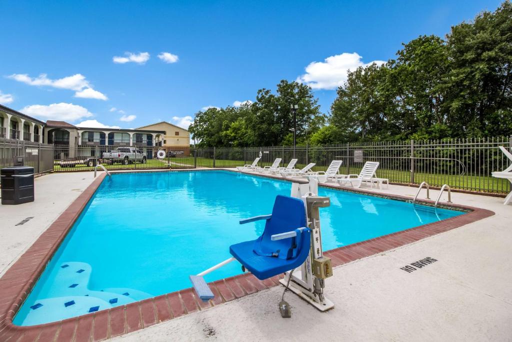 uma piscina com cadeiras e uma poltrona reclinável azul em Motel 6 Groves, Tx em Groves