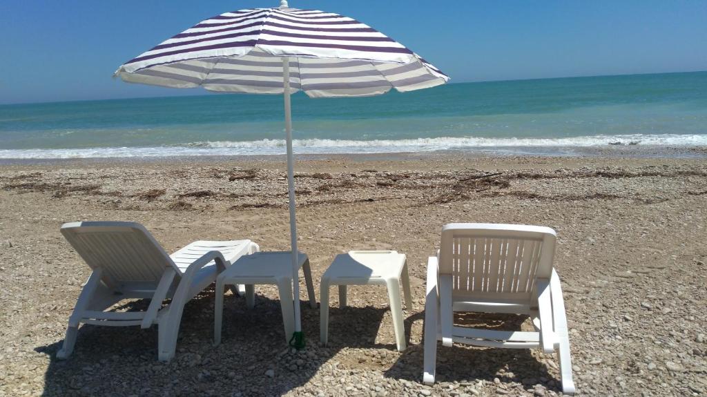 two chairs and an umbrella on the beach at VILLAGGIO degli ANGELI SCERNE PINETO in Scerne