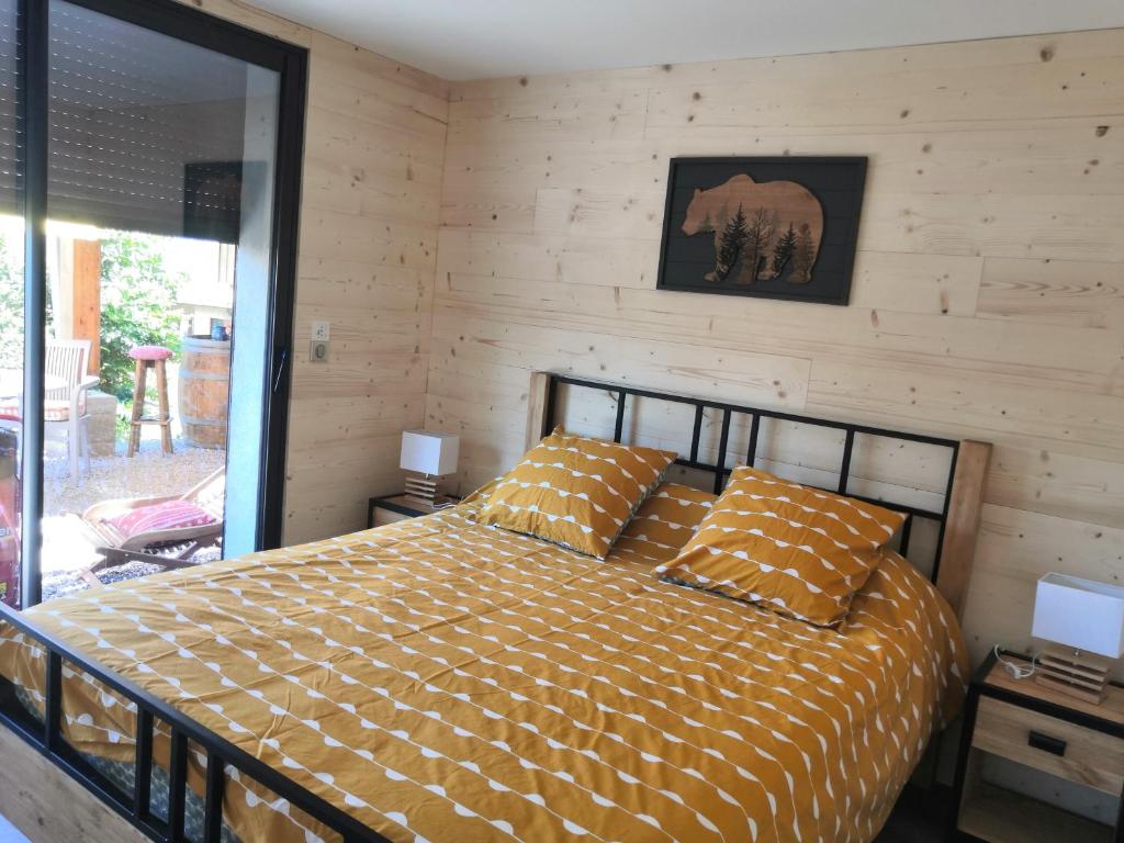 - une chambre avec un lit et un mur en bois dans l'établissement Gîtes Les Garianes, à Saint-Léger-les-Mélèzes