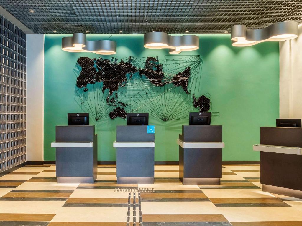 eine Lobby mit einer grünen Wand mit Wandmalereien darauf in der Unterkunft ibis Styles SP Centro in São Paulo