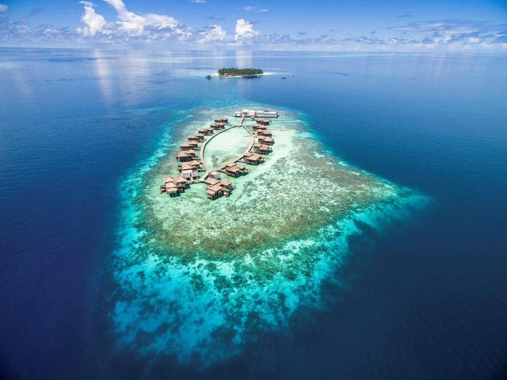 an island with a resort in the middle of the ocean at Raffles Maldives Meradhoo in Gaafu Alifu Atoll