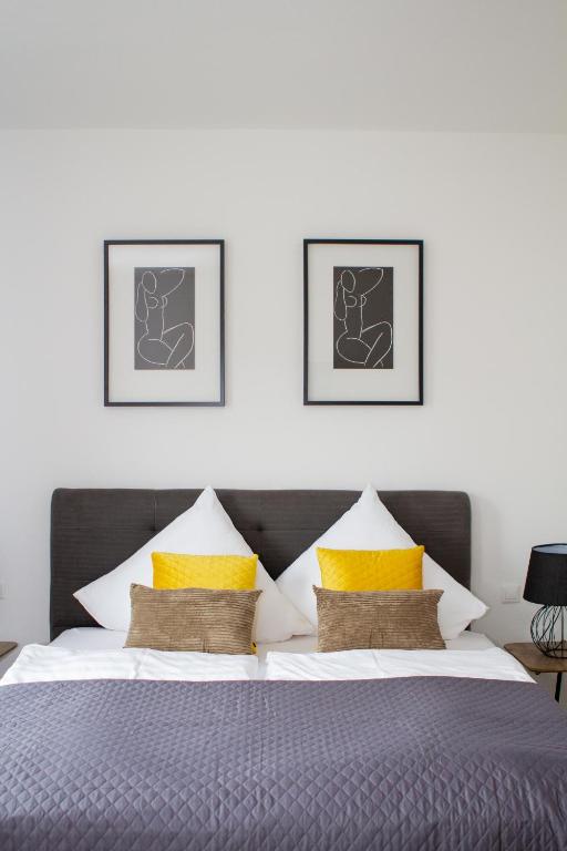 Un dormitorio con una cama grande con almohadas amarillas. en Stadthotel Marburg, en Marburg an der Lahn