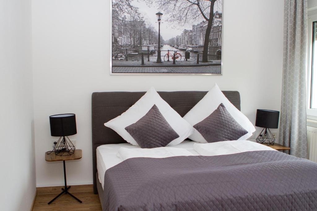 1 dormitorio con 1 cama con 2 lámparas y una foto en la pared en Stadthotel Marburg, en Marburg an der Lahn