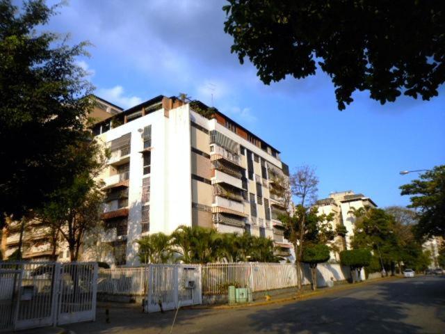 un gran edificio blanco en una calle de la ciudad con árboles en Apartamento tipo estudio, en Caracas