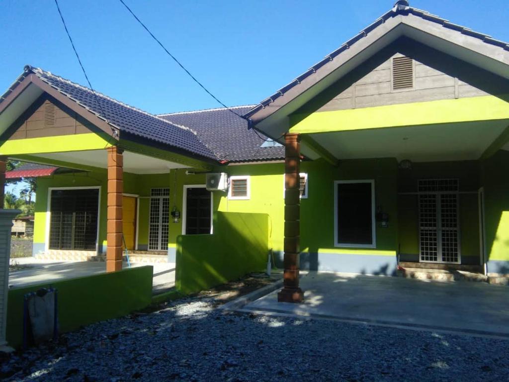 uma casa com tinta verde e amarela em Homestay D ARYNIE em Bukit Payong