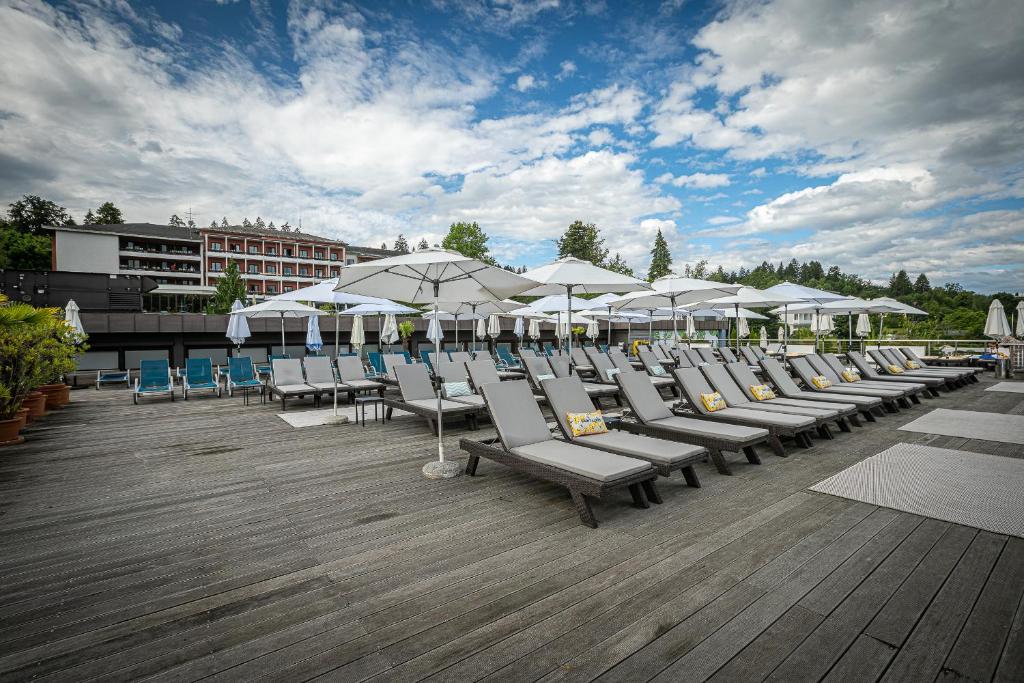 eine Reihe von Liegestühlen und Sonnenschirmen auf einer Terrasse in der Unterkunft Hotel Parks in Velden am Wörthersee