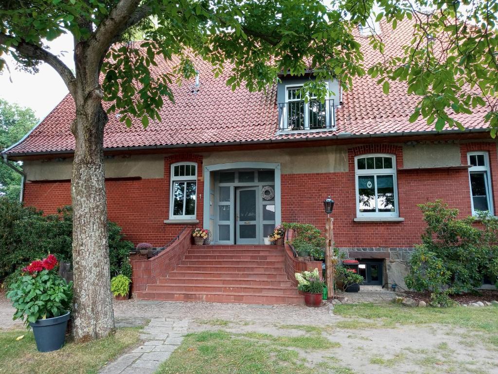 een rood bakstenen huis met een boom en een trap bij Storchenhof in Wrestedt