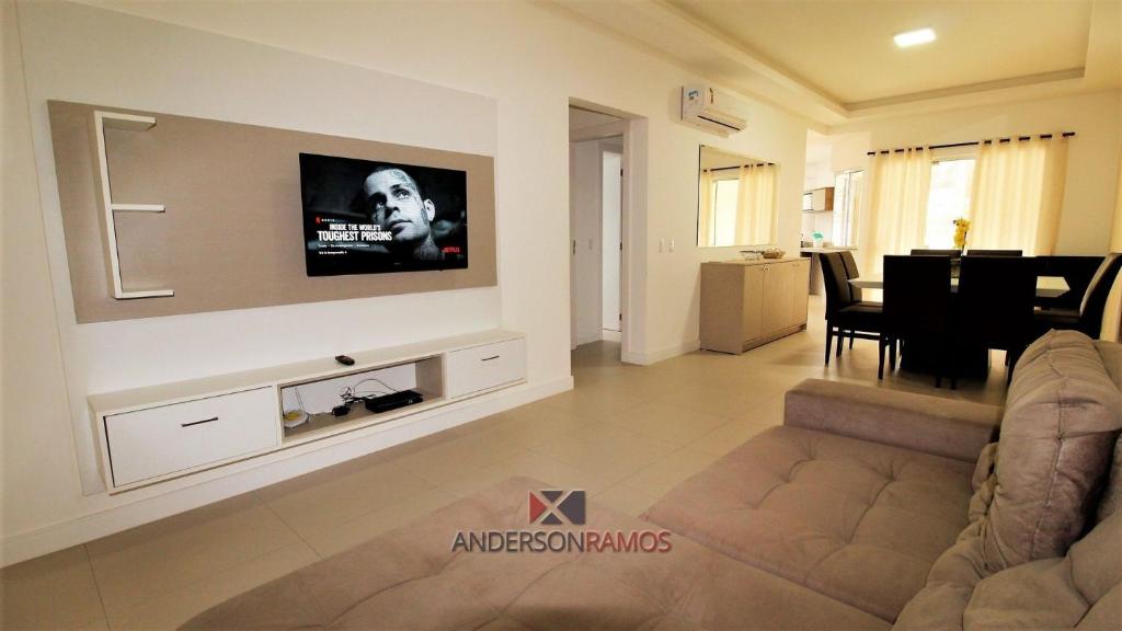 a living room with a couch and a tv on the wall at 1068 - Apartamento com vista para o mar in Bombinhas