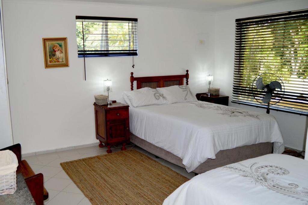 a white bedroom with two beds and a window at Clubmed 23 in Hibberdene