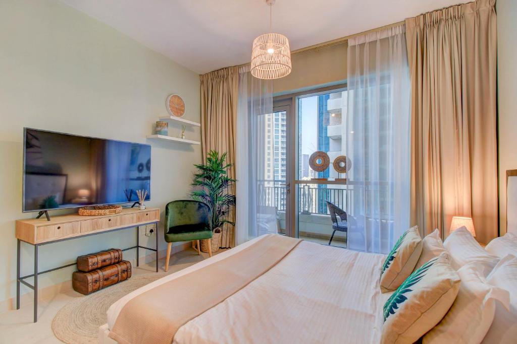 a bedroom with a bed and a desk and a television at Durrani Homes - Luxurious Studio near Dubai Mall with pool view in Dubai