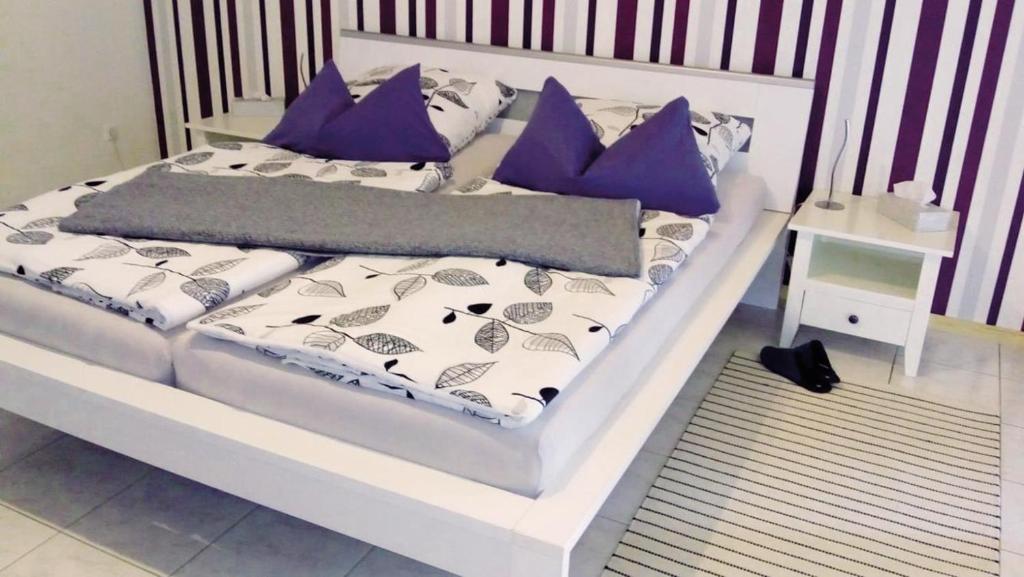 Una cama con almohadas moradas y blancas. en Appartement Schönberger, en Rodder