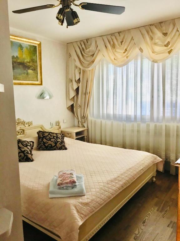 a bedroom with a bed with a ceiling fan and a window at Avelana Apartment in Pärnu