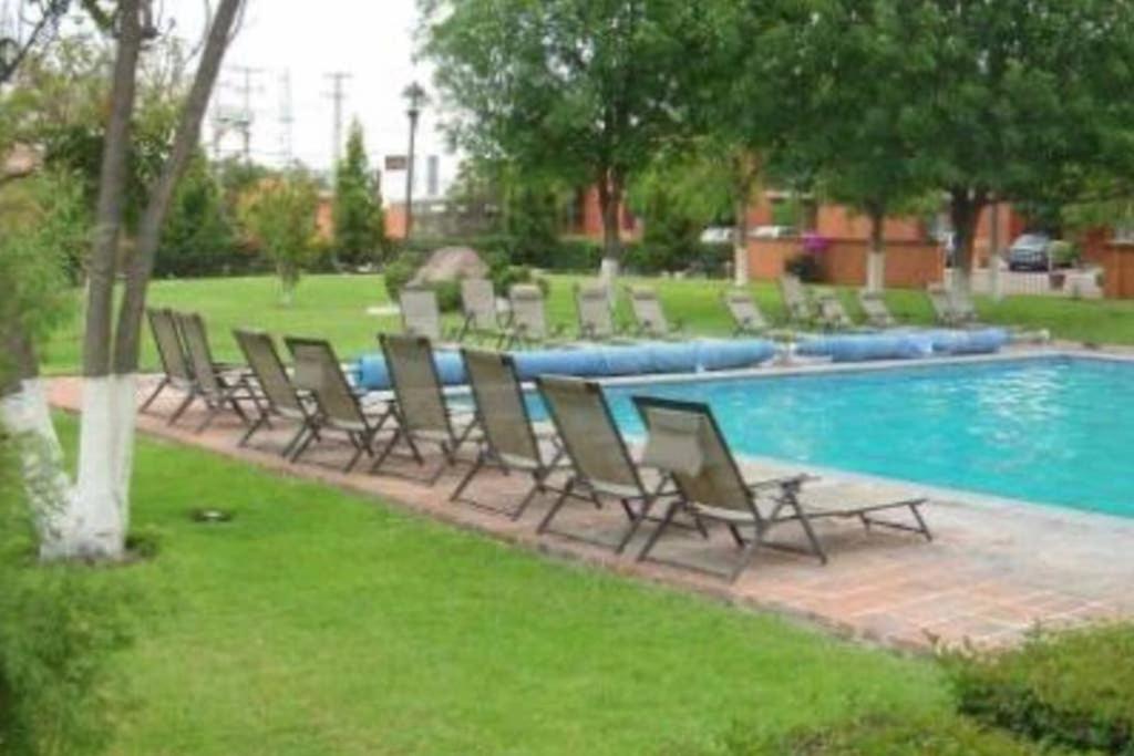 - un groupe de chaises assises à côté de la piscine dans l'établissement Amplia Suite Alberca Av Bernardo Quintana 12D, à Mendiola