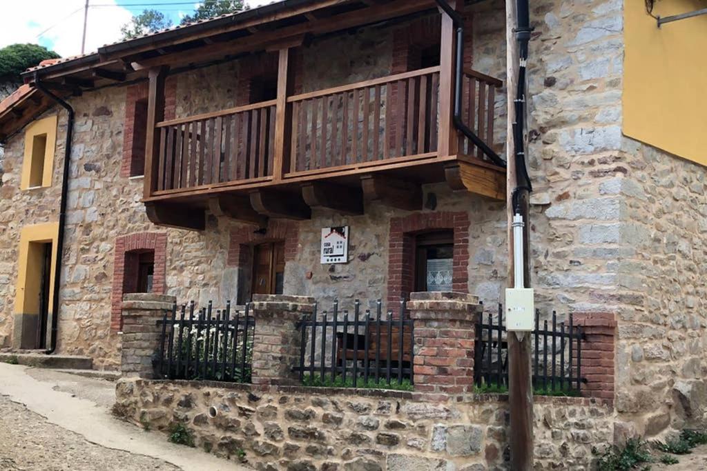 a stone building with a balcony and a fence at La Casita de Verdiago in Verdiago