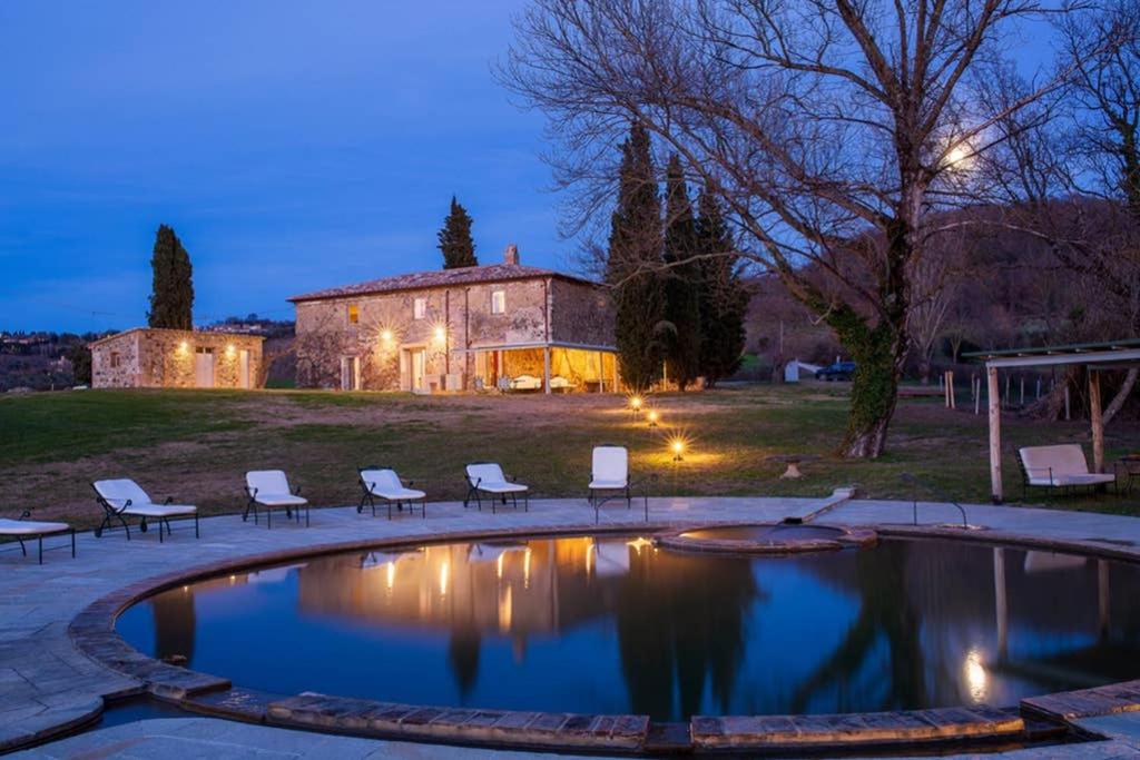 a large pool with chairs and a house in the background at Podere La Piscina- Acqua Termale e Relax in San Casciano dei Bagni