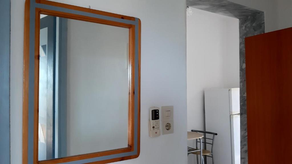 a mirror on a wall next to a refrigerator at House Anna Houhlia in Vourvourou
