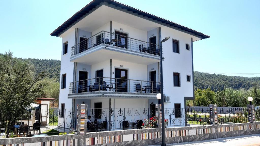 a white house with balconies and a fence at House Anna Houhlia in Vourvourou
