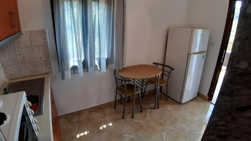 a small kitchen with a table and a refrigerator at House Anna Houhlia in Vourvourou