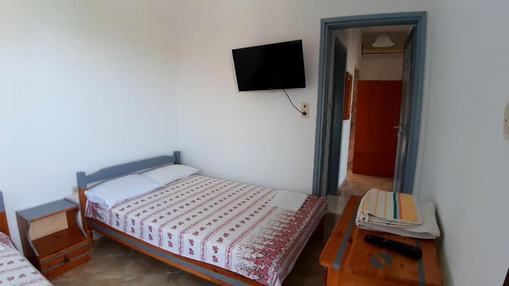 a bedroom with a bed and a tv on the wall at House Anna Houhlia in Vourvourou