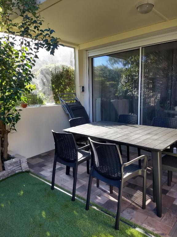 une table et des chaises en bois sur une terrasse dans l'établissement Particulier loue T3 en rez de jardin à 30 mètres de la plage avec un double box, à La Ciotat