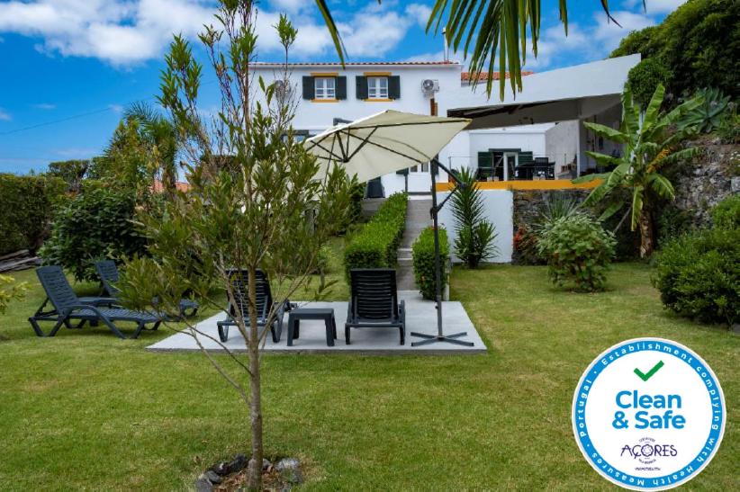 a garden with chairs and an umbrella in front of a house at Casa da Quinta in Vila Franca do Campo