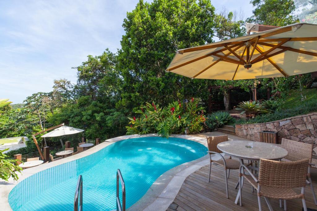 a swimming pool with a table and an umbrella at Pousada Vila do Bosque in Bombinhas
