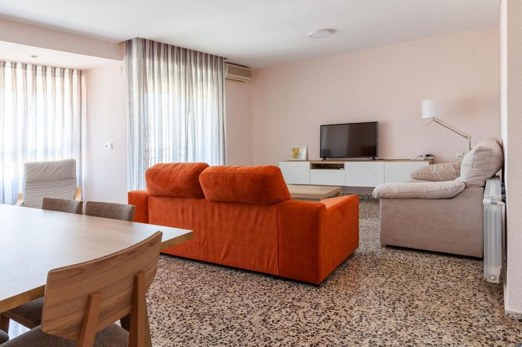 sala de estar con sofá naranja y TV en Apartamento Sambala, en Ontinyent