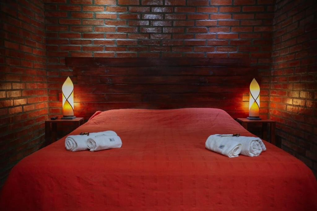 a bedroom with a red bed with two towels on it at Posada Madre America in San Ignacio