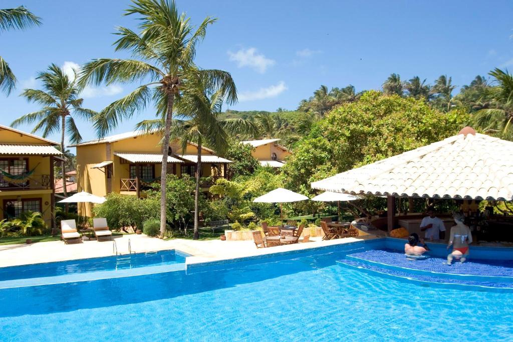a pool at a resort with two people in it at Pousada dos Girassóis in Pipa