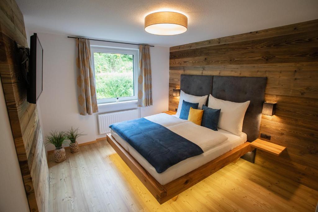 ein Schlafzimmer mit einem großen Bett und einer Holzwand in der Unterkunft Apartment Vera in Saalfelden am Steinernen Meer