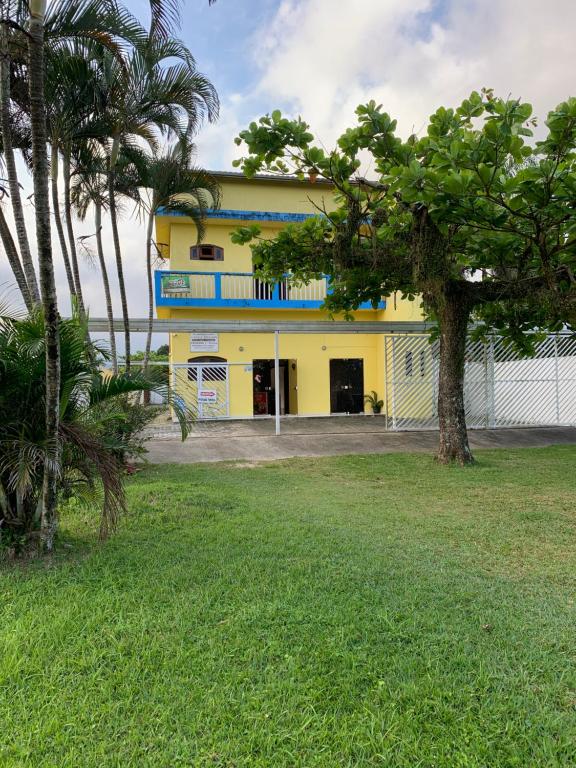 un bâtiment jaune avec un balcon bleu et des palmiers dans l'établissement Pousada Bertimar, à Bertioga