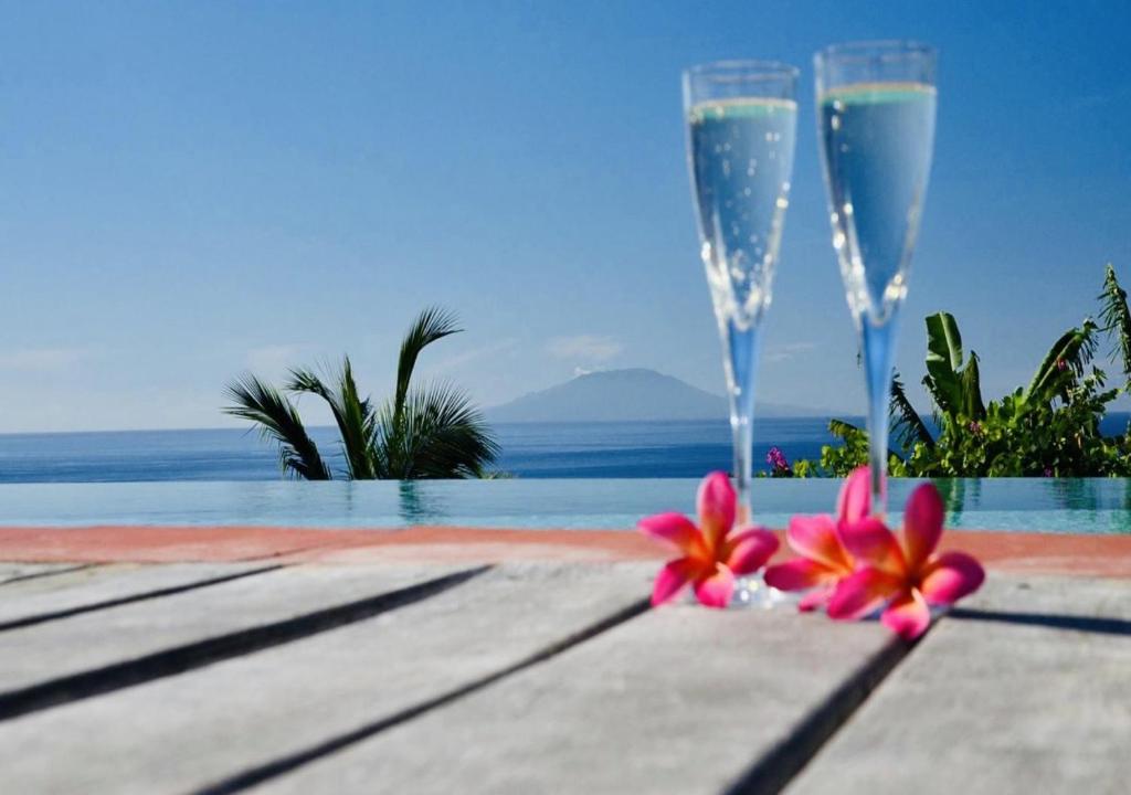 two champagne glasses and flowers on a table next to a pool at Tet Rouge Resort in Soufrière