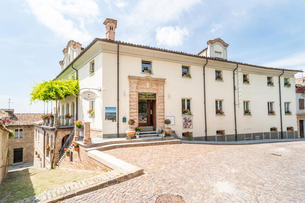 una vista exterior de un gran edificio blanco en Borgo Vecchio Locanda di Charme, en Neive