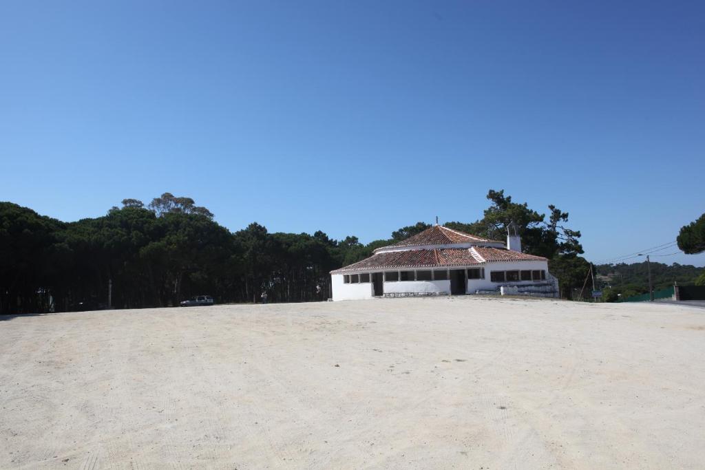 a building on top of a sandy beach at ribeira dos marinheiros amarelo in Sintra