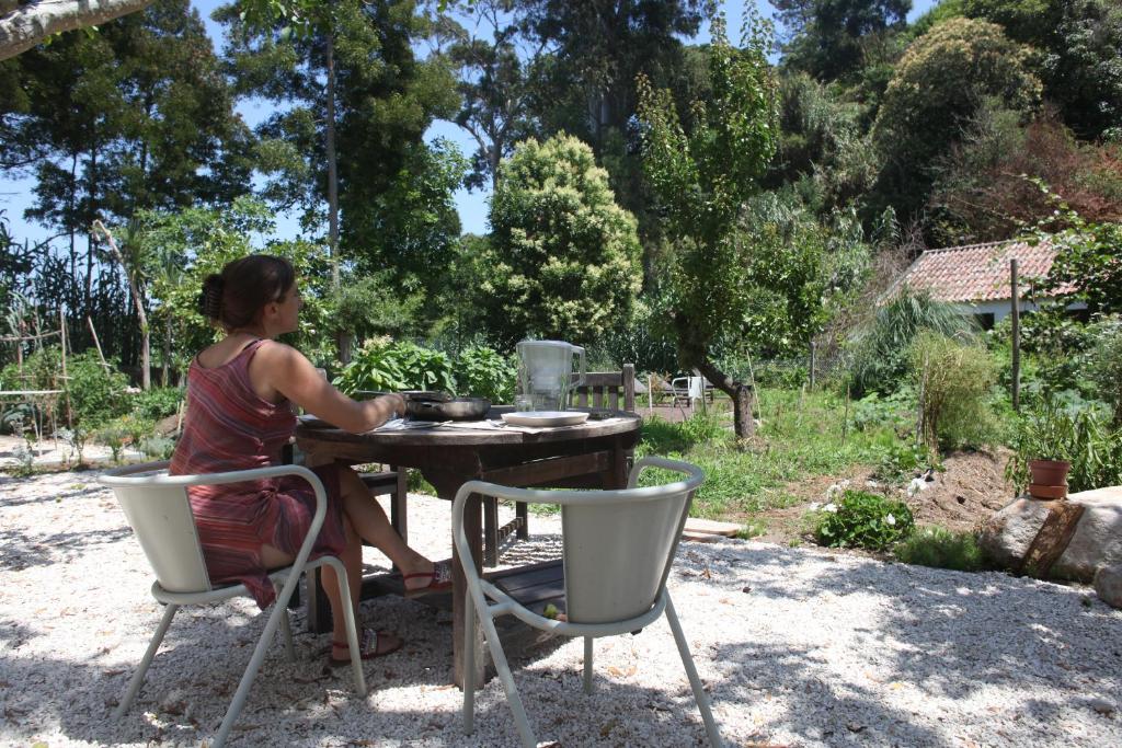 a woman sitting at a table in a garden at ribeira dos marinheiros amarelo in Sintra
