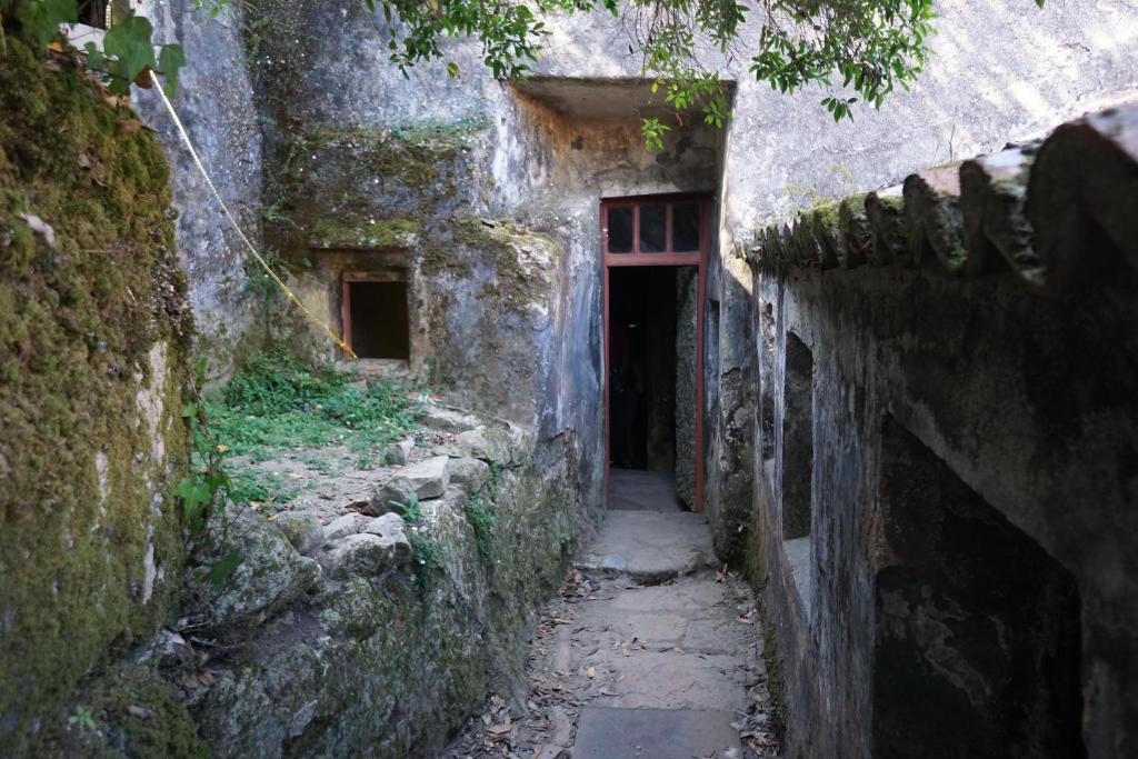 an alley in an old stone building with a red door at ribeira dos marinheiros amarelo in Sintra