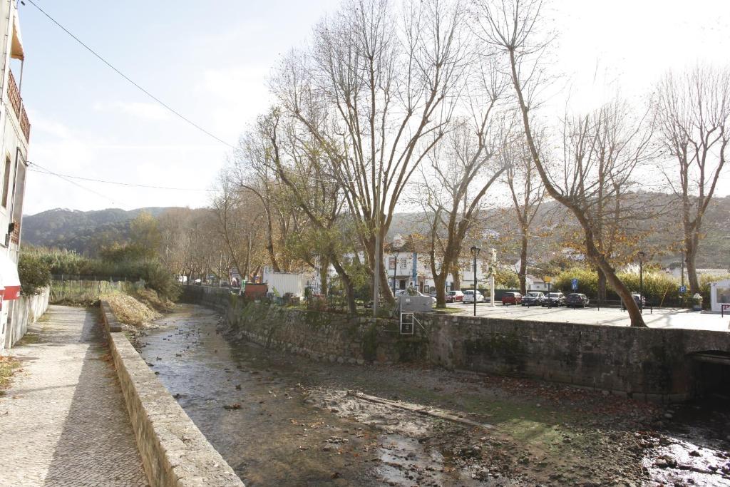 a river next to a stone wall next to a street at ribeira dos marinheiros amarelo in Sintra